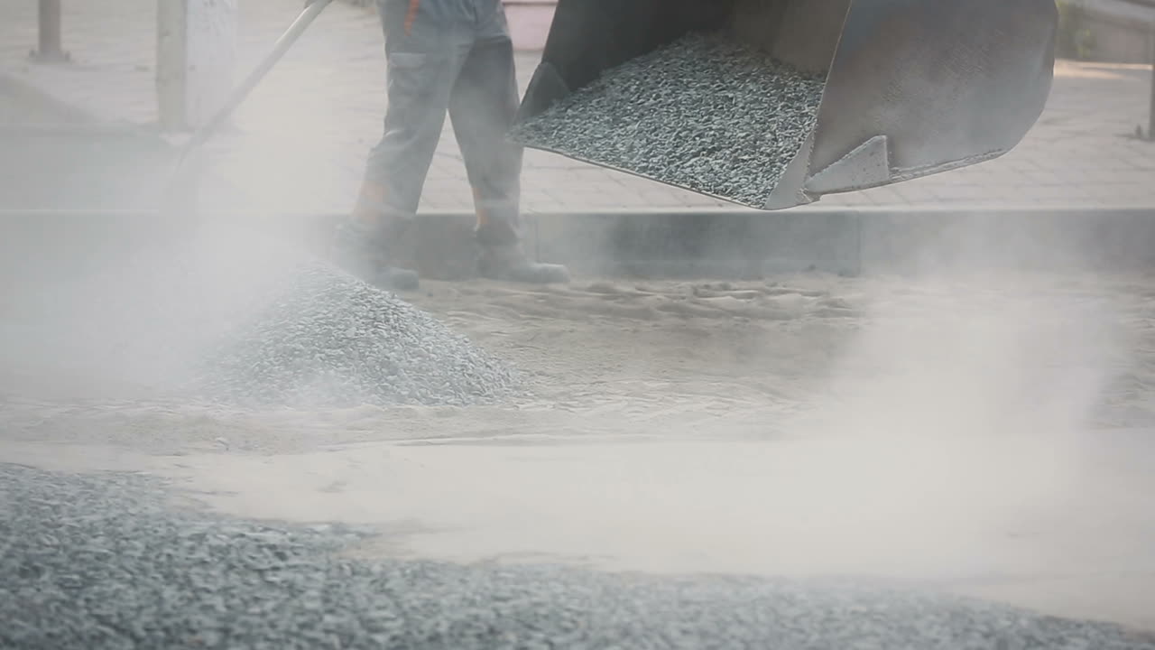 Manual Labor On Construction Site. Construction workers during asphalting road works wearing coveralls