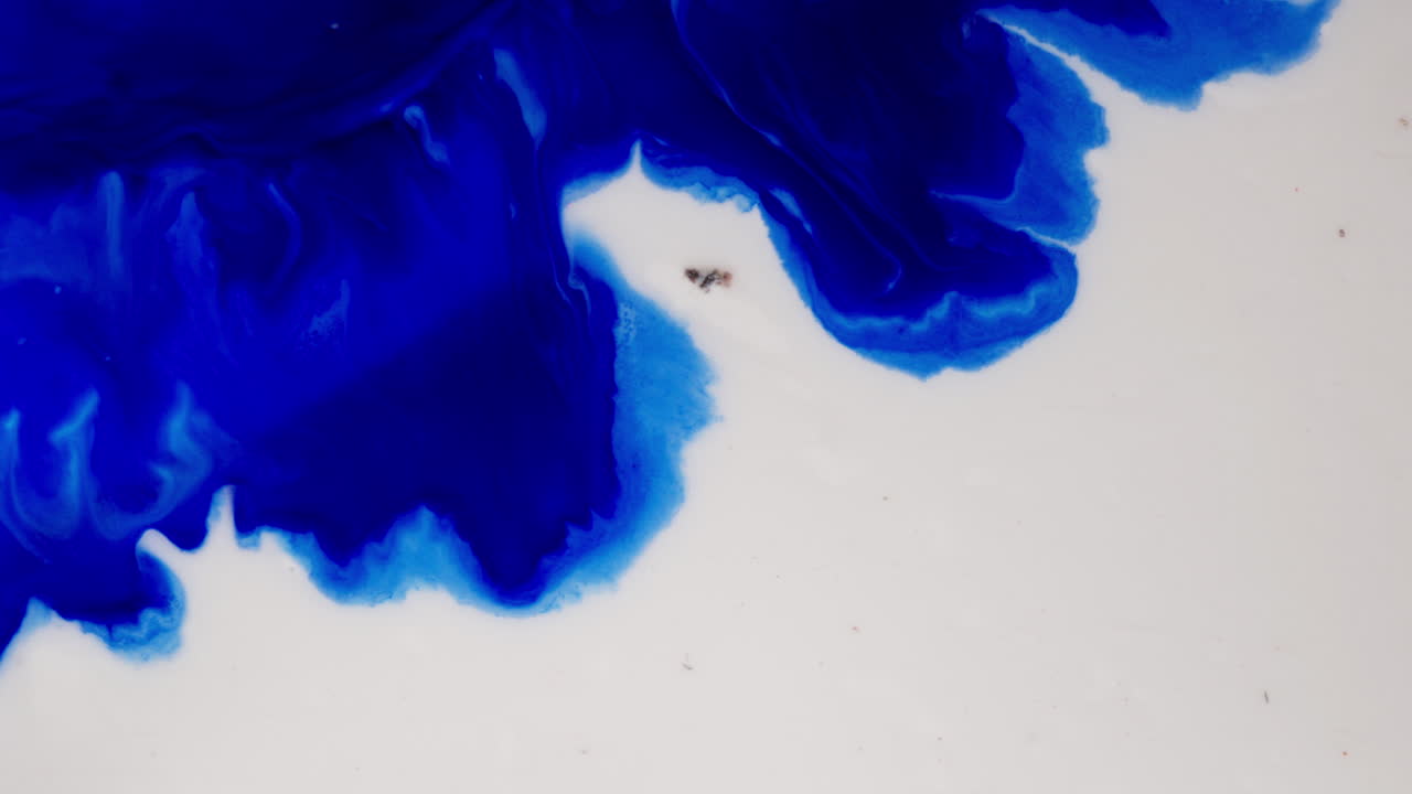 Deep Blue Ink Surfacing In White Backdrop. Abstract