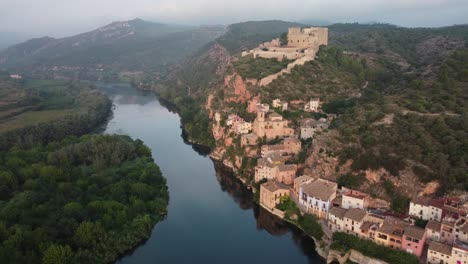 drone view approaching miravet, view of castle, town and ebro river