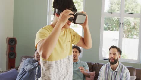 happy diverse male friends using vr headset and talking in living room