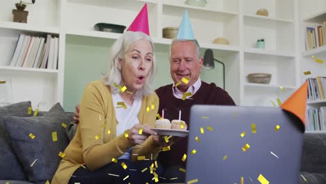 animation of confetti falling over senior couple in party hats on laptop video call