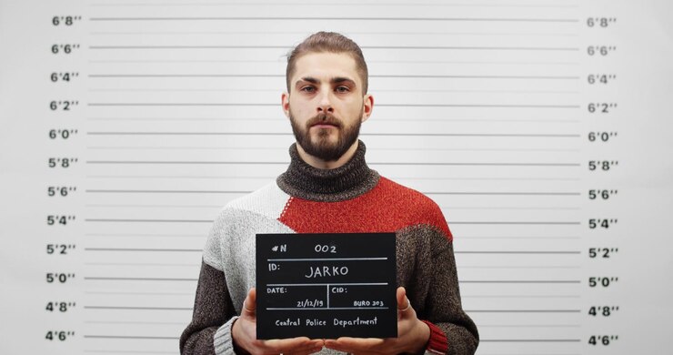 Ung mand holder skilt til forbryderfoto på politistation