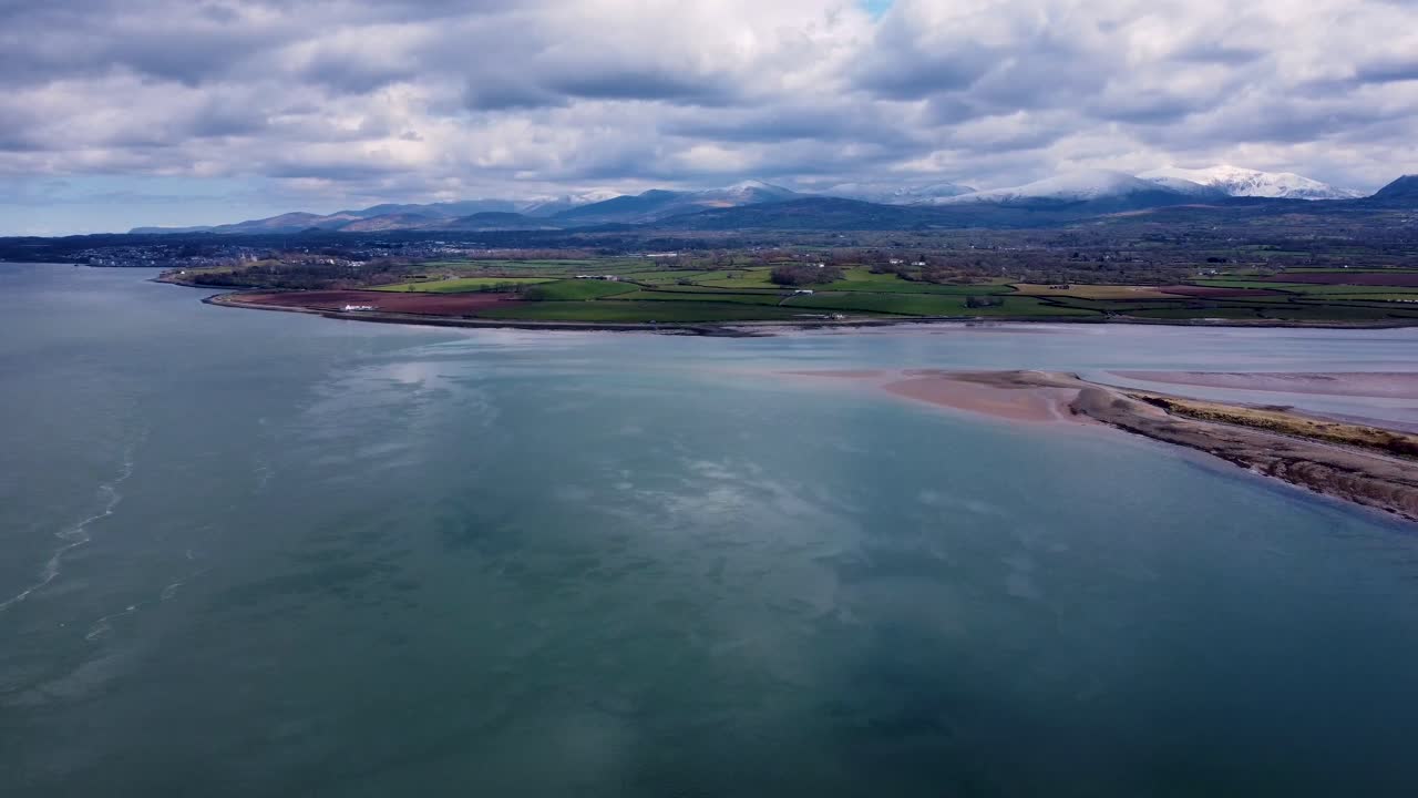 Drone footage looking over the Menai Straits in north Wales towards the Snowdonia mountain range, North Wales, UK