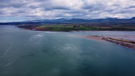 Drone-footage-looking-over-the-Menai-Straits-in-north-Wales-towards-the-Snowdonia-mountain-range,-North-Wales,-UK