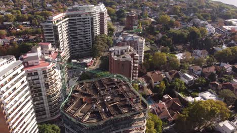 Work-in-progress-at-construction-site-with-crane-on-top-of-building-in-Buenos-Aires-in-Argentina,-cityscape-in-background