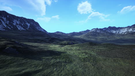 aerial view of a mountain range with green grass and snow