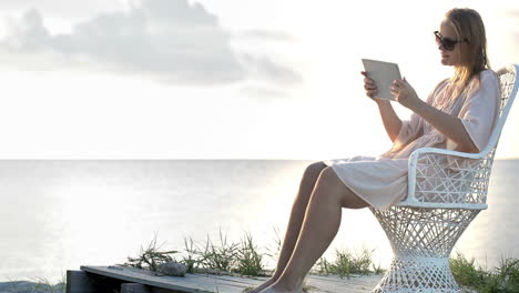 woman near the sea watching photos using pad