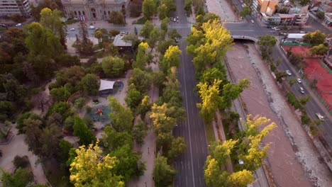 Vehicles-passing-along-a-road-next-to-a-park-in-the-center-of-a-large-city