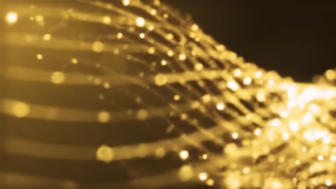 Mesmerizing golden wave patterns flow smoothly, illuminated by sparkling light effects. This captivating backdrop creates a luxurious atmosphere perfect for celebrations or events.