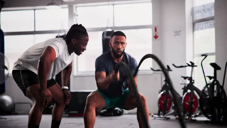 men working out with a battle rope in a gym