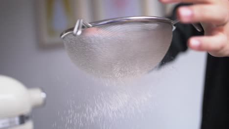 baker taps sieve of flour slow mo