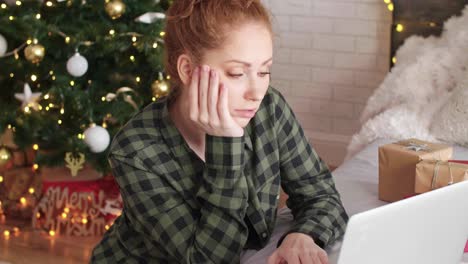 mujer aburrida usando computadora portátil en el dormitorio