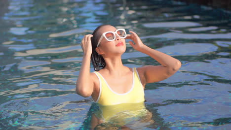 sexy sensual mujer suave cabello mojado con las manos mientras camina dentro de la piscina exótica en bali, indonesia, cámara lenta retrato vista frontal mirada soñadora al atardecer