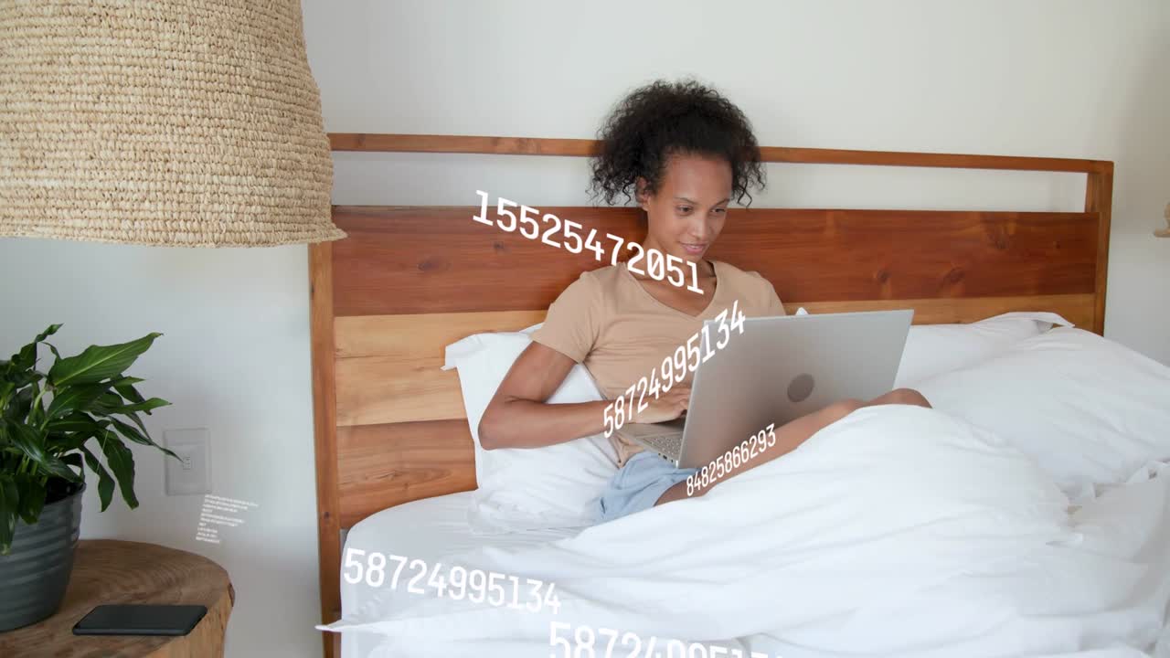 Woman in bed typing laptop, causing data overlays circling laptop and phone for tech work