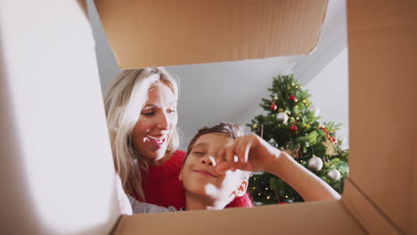 mother and son opening present on christmas morning viewed from inside box