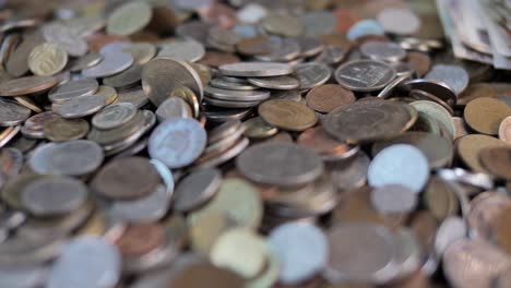 close up on coins falling on pile of money, selective focus