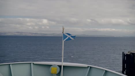 a ferry leaves the mainland of scotland heading for arran with the saltire flag flying in the wind