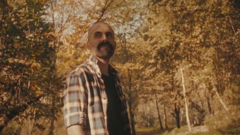 young man in forest enjoys golden light through trees. he feels warm and relaxed in nature. perfect clip for nature or self-development projects.
