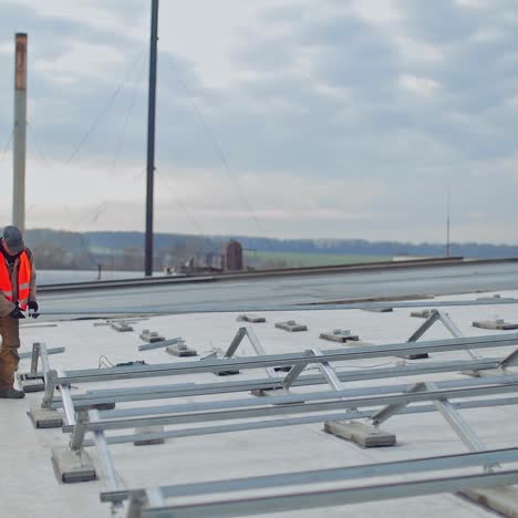 metal construction on the flat roof of the building. two workers installing metal base for future solar panels in the new solar power plant.