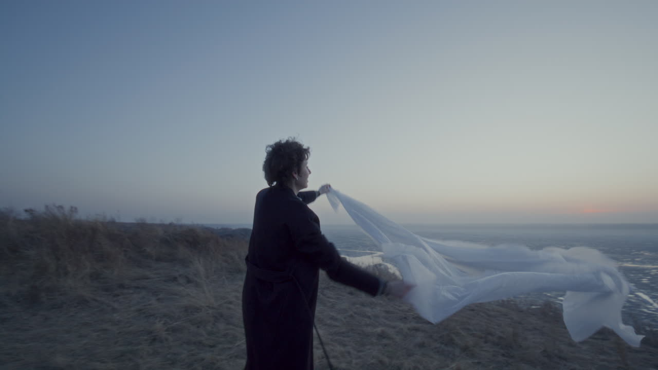 Cheerful Woman Spinning with Translucent Fabric by Frozen Lake