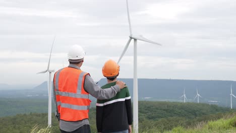 progressive engineer with his son in the wind farm atop of the mountain.