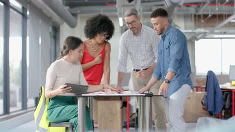 Team-of-diverse-architects-discussing-over-a-plan-at-office