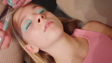 Young-female-child-laying-down-has-her-eyelids-painted-turquoise