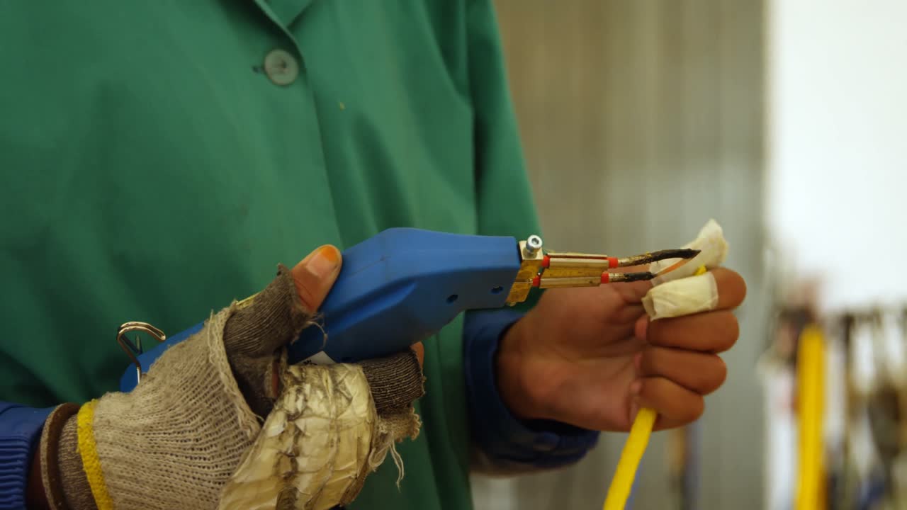 trabajador que utiliza una pistola de corte de cuerdas en la industria de fabricación de cuerdas 4k