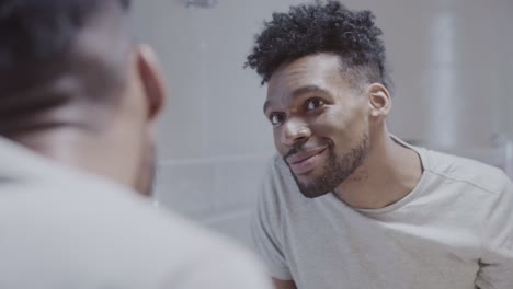 man applying skincare product to his face in the mirror
