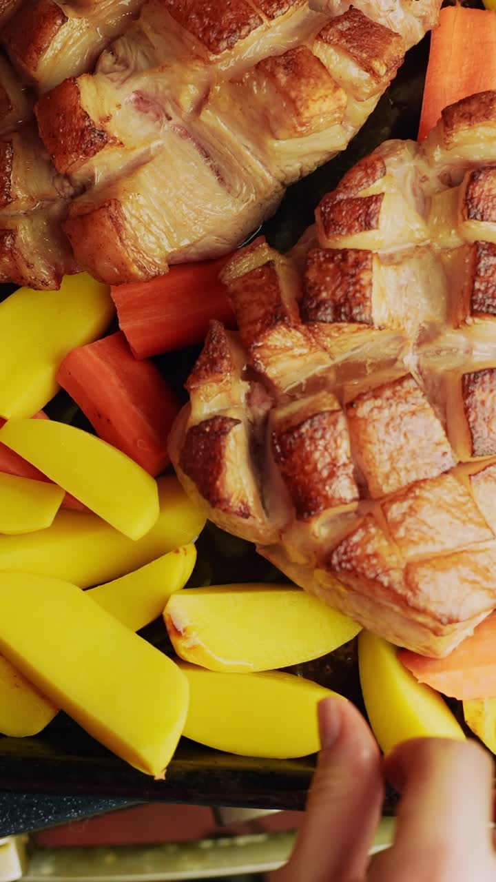 Primo piano verticale dell'aggiunta di patate a spicchi a una teglia da forno con pollo e carote, preparazione rustica casalinga per la cena arrosto.