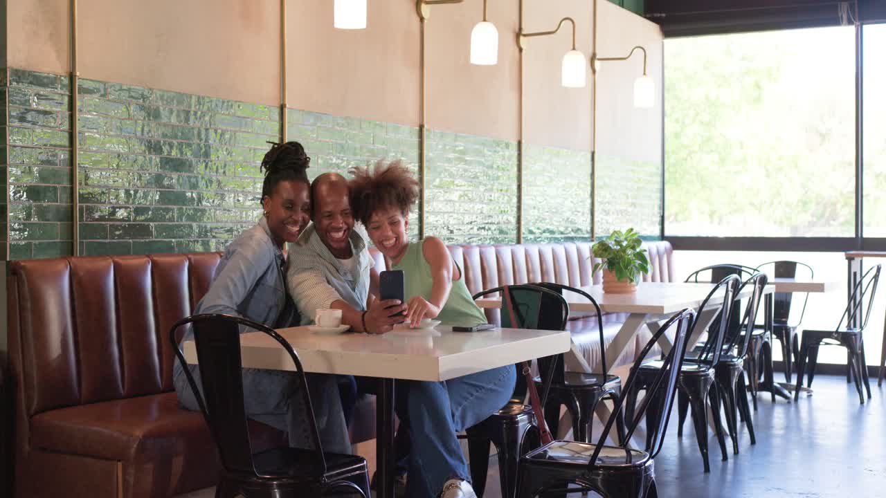 African American pals coffee cups at cafe, man entering hugging showing phone taking selfie leaving