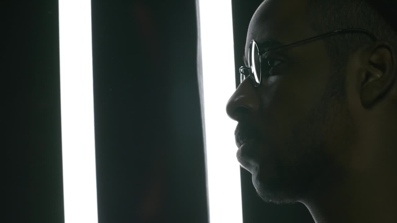 hombre negro con gafas posando en un estudio oscuro