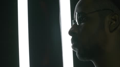 black man in glasses posing in dark studio