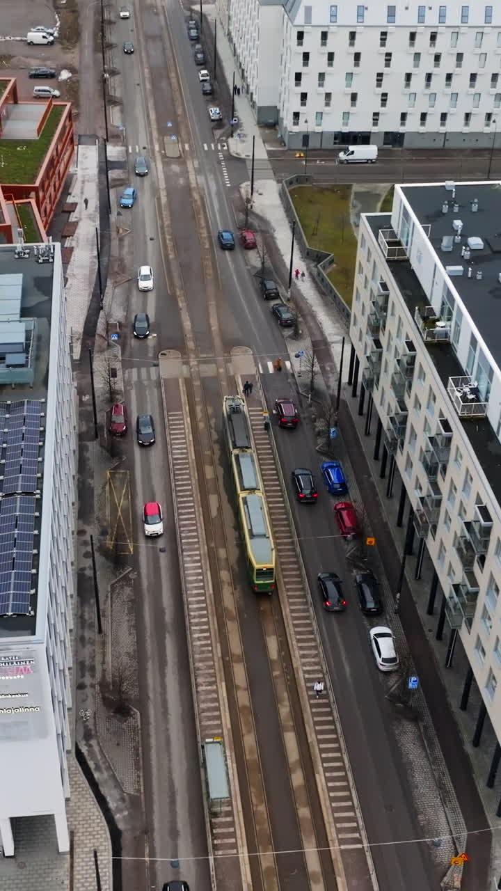 Aerial portrait orbiting a tram on the streets of Jatkasaari, cloudy Helsinki