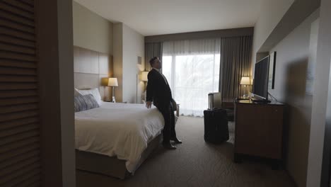 business man in suit entering hotel room - exhausted falling back on bed