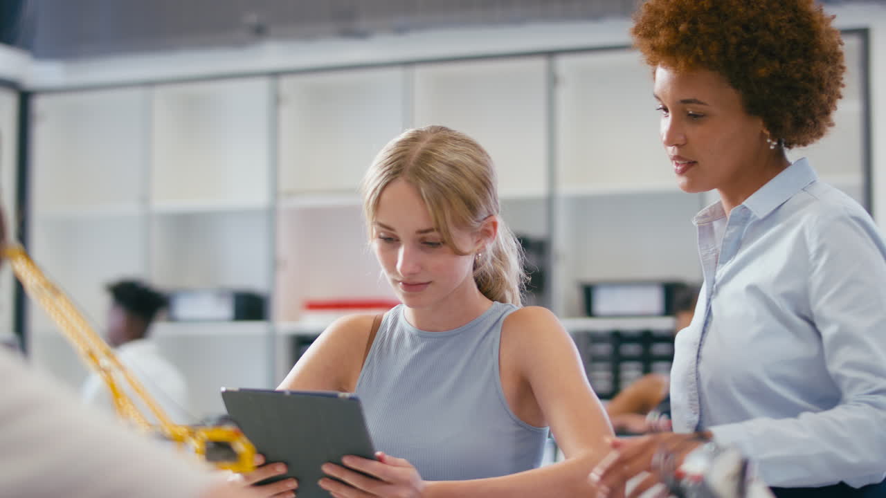 Female Teacher With Female High School Student Using Digital Tablet In STEM Class