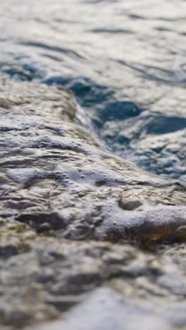 close up vertical view of water waves reach rocky coast, mallorca