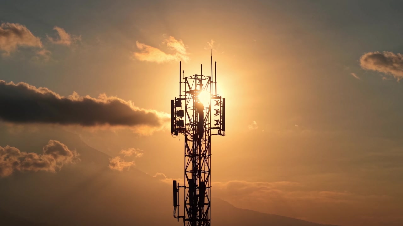 Torre di rete cellulare sagomata contro un tramonto drammatico con nuvole. Filmato concettuale su telecomunicazioni, segnale e tecnologia wireless