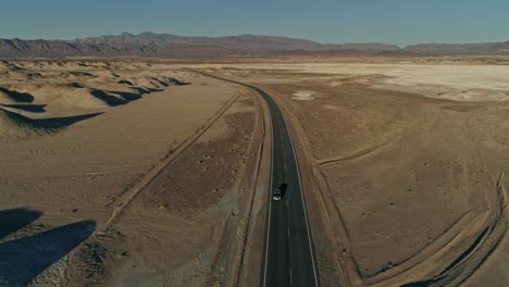 high aerial view following a highway bend with moving cars in the desert