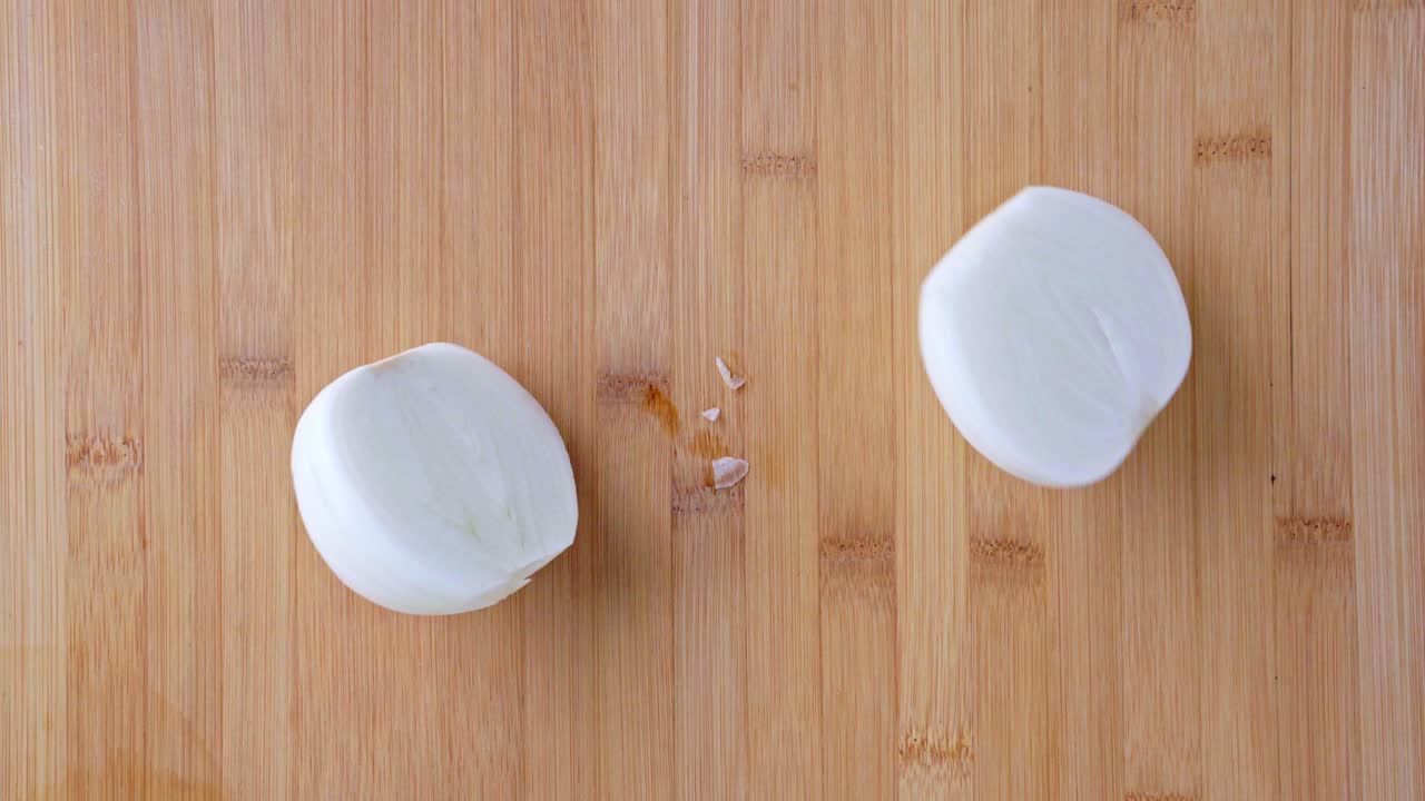 요리사는 칼로 양파를 절단판에 잘라 새 양파를 반으로 잘라 건강한 채소와 음식, 생 양파를 색 테이블 배경에 놓습니다.