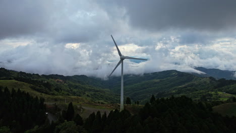 Wind-turbine-aerial-shot-on-a-hill-full-of-dense-vegetation