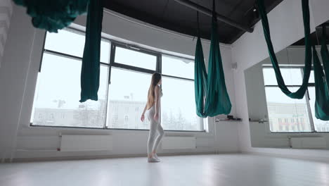 a young woman in slow motion prepares to begin a stretching and yoga class on a hammock. straighten the developing hammock tissue before training