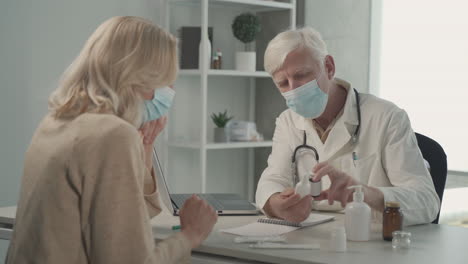 a grey haired, middle aged doctor in a facemask prescribes medicines to a female patient