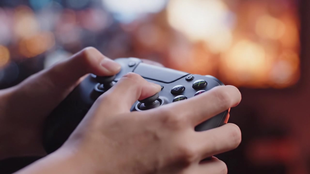 Engaging Gameplay: A Close-Up of Hands Skillfully Maneuvering a Game Controller, Immersed in a Vibrant, Colorful Gaming Environment.