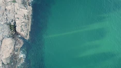 drone traveling along blue rocky ocean shore at sunset