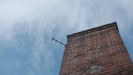 light clouds passing behind brick chimney with tv antennae