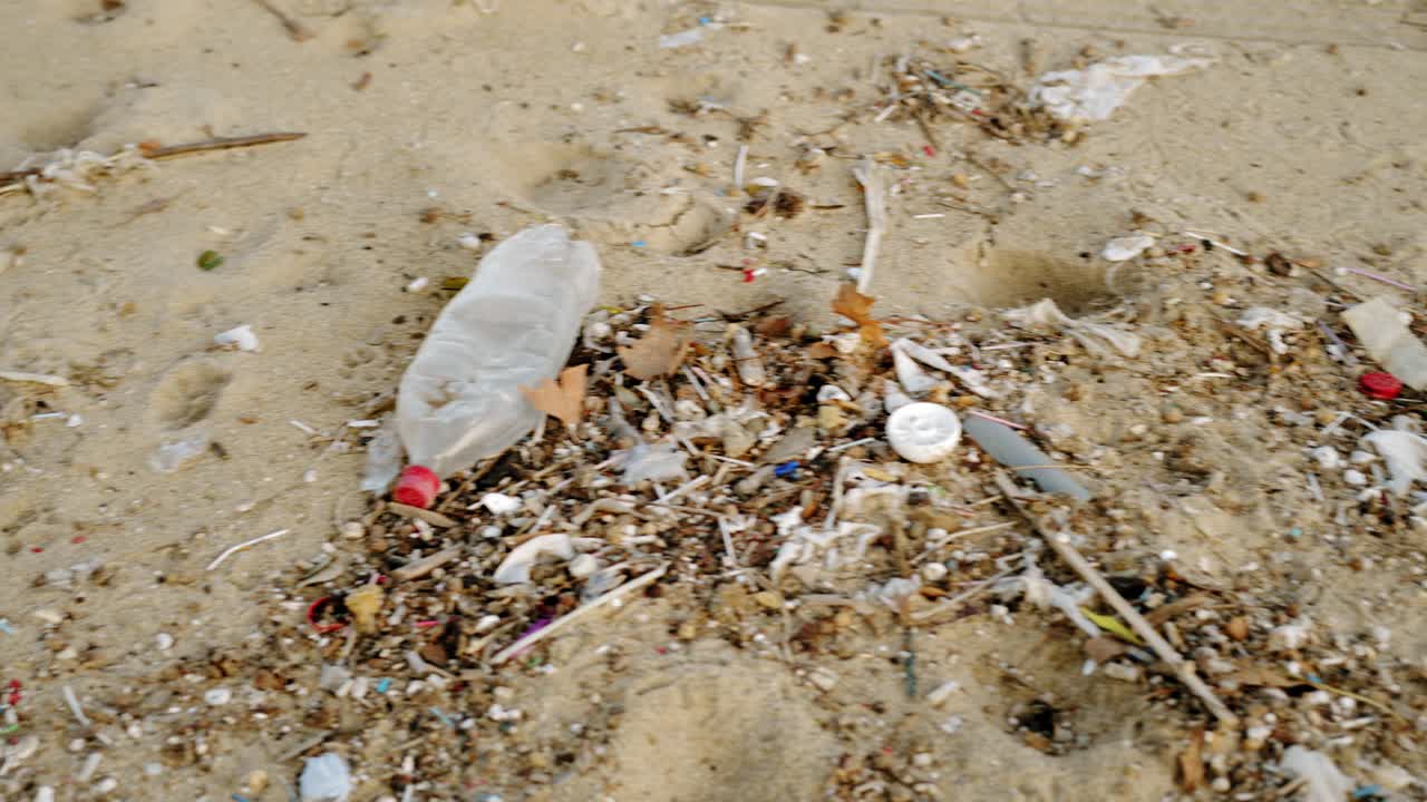 Beach sand full of microplastic garbage waste due to Climate change and unsustainable Environmental pan medium shot