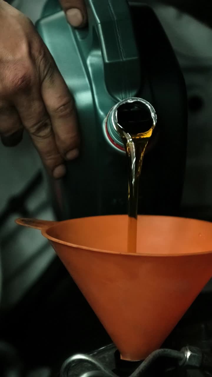 Mechanic Pouring Fresh Engine Oil into a Car with a Funnel