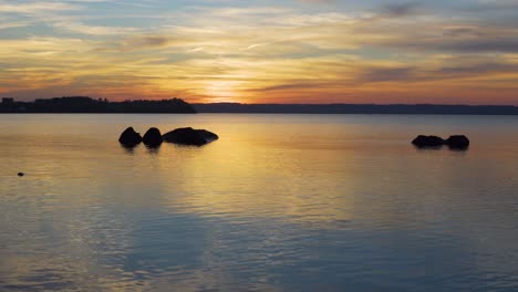 puesta de sol hermosa, tranquila y tranquila con pequeñas olas en un lago