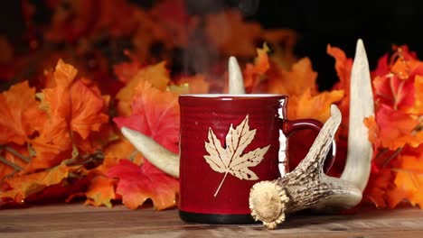 fall themed setting, red mug or cup with a maple leaf, whitetail deer shed antler and color maple leaves